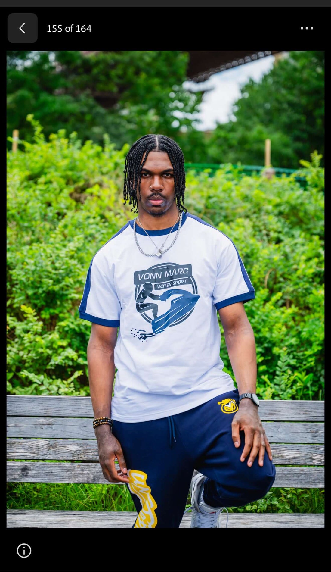 VONN MARC blue Jet Ski T- Shirts model posing outdoors on a bench with greenery in the background.