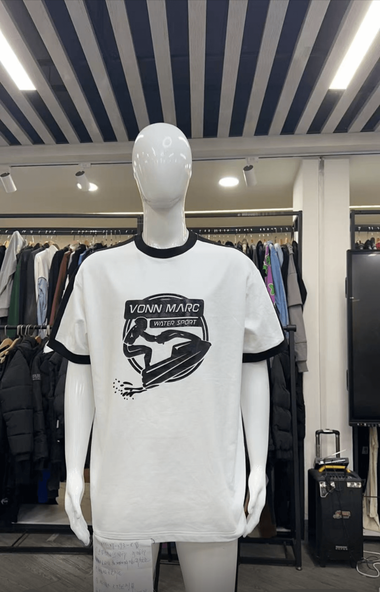 White t-shirt with black graphics on a mannequin in a clothing store.