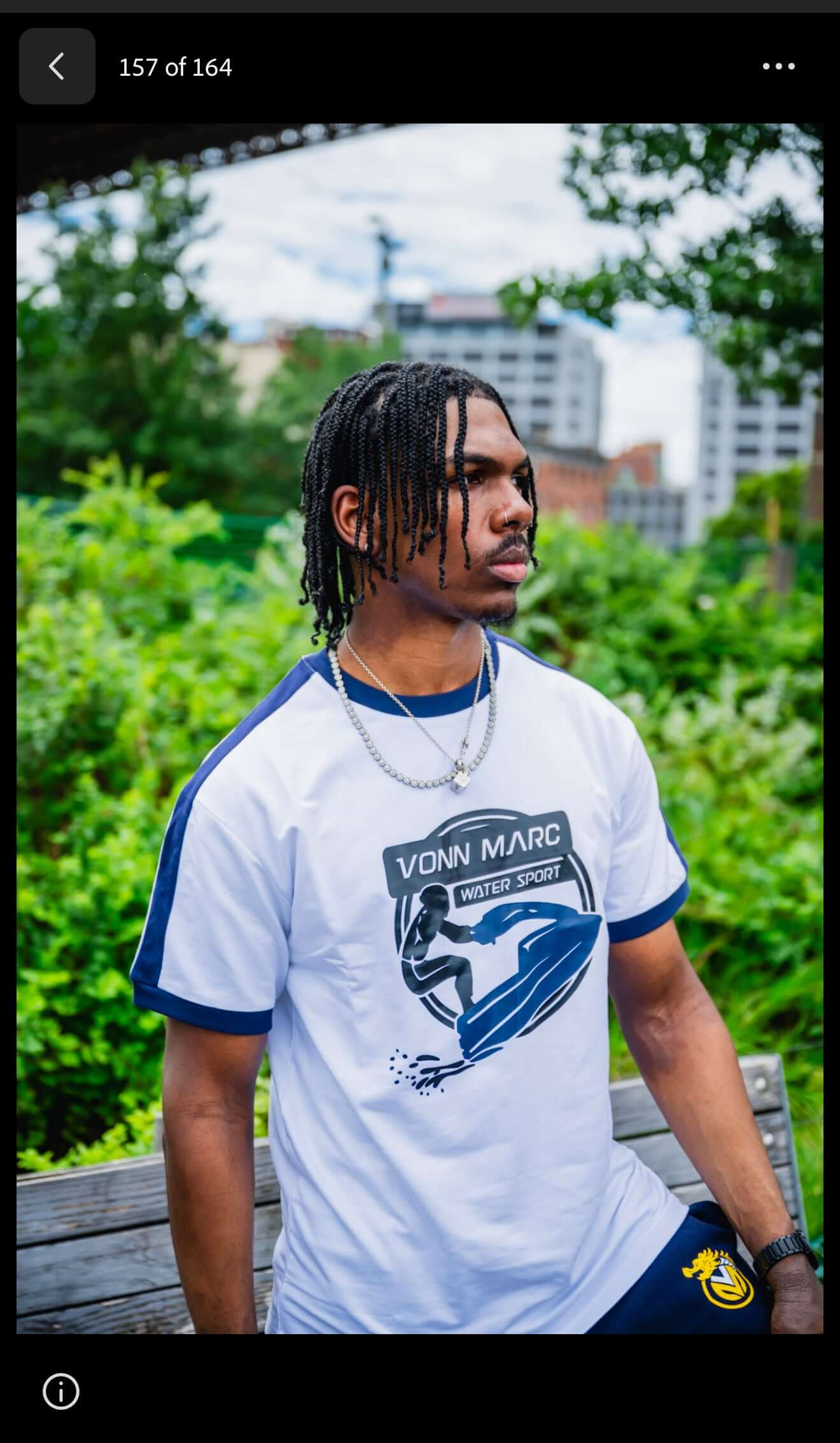 VONN MARC blue Jet Ski T- Shirts model posing outdoors on a bench with greenery in the background.